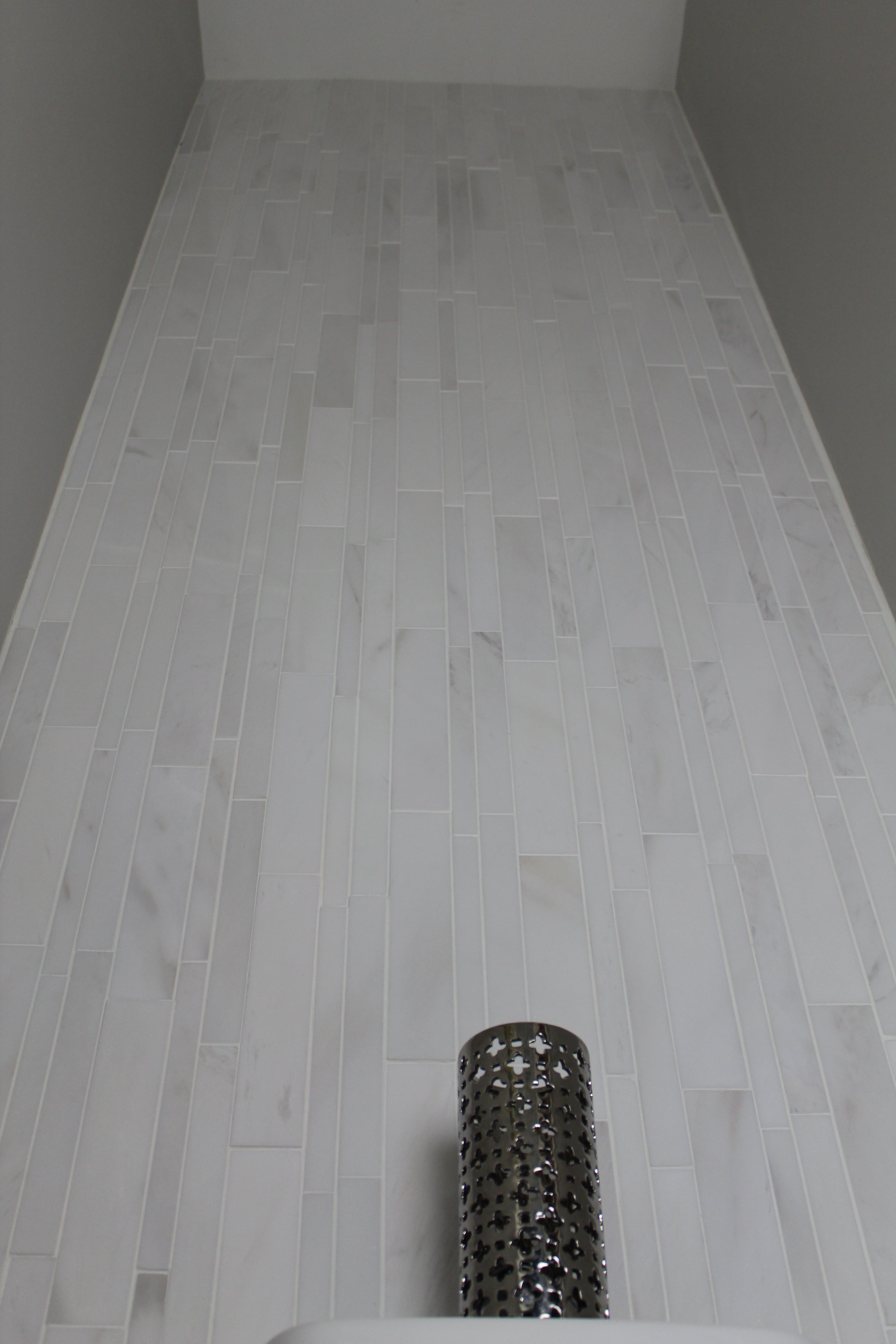 Norstone White Marble Lynia Tile Installed as a feature wall in a powder bathroom with high ceilings